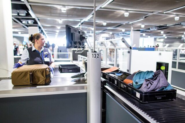 Eine Flughafenmitarbeiterin arbeitet am Flughafen Düsseldorf bei der Sicherheitskontrolle.