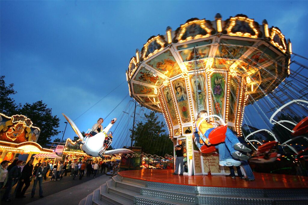 Besucher sitzen auf der Bartholomäuskirmes in Lütgendortmund im Kettenflieger. Besucher sitzen auf der Bartholomäuskirmes in Lütgendortmund im Kettenflieger.