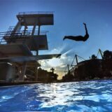 Ein Mann springt im Freibad Volkspark in Dortmund vom Sprungturm ins Schwimmbecken.