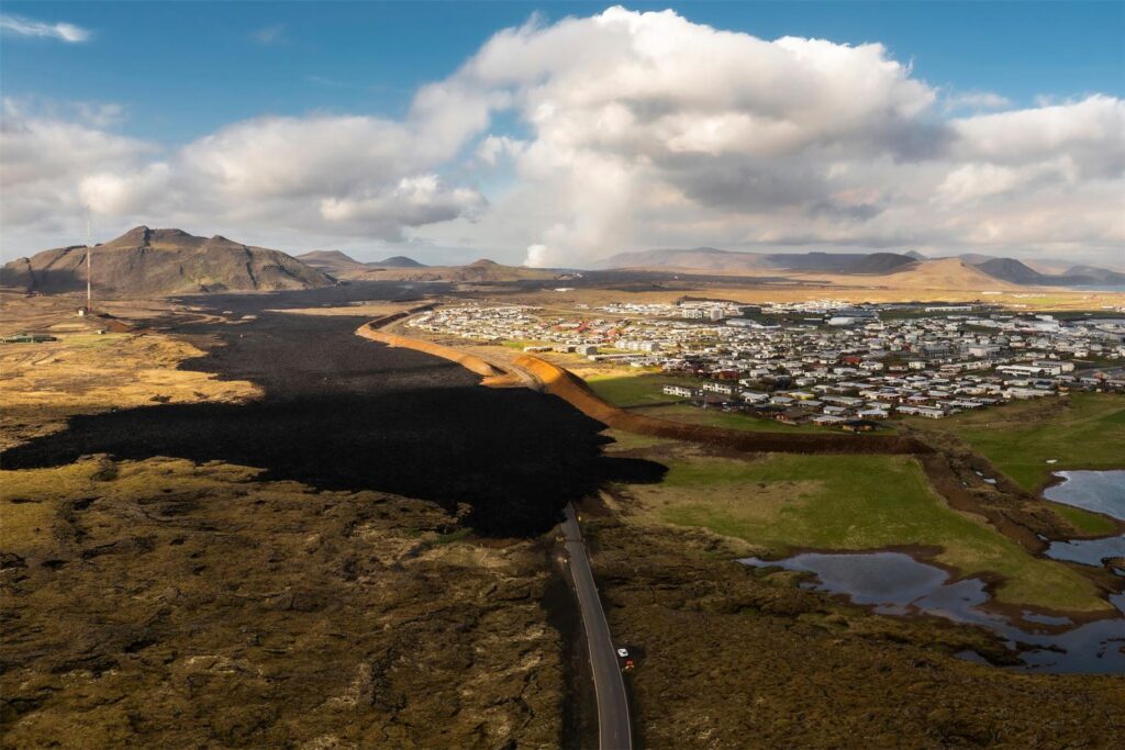 Lavastrom aus einem Vulkan in Grindavík, Island, bedeckt eine Straße. Lavastrom aus einem Vulkan in Grindavík, Island, bedeckt eine Straße.