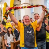 Ein Fan im BVB-Trikot hält in der Kirche einen Schal hoch.