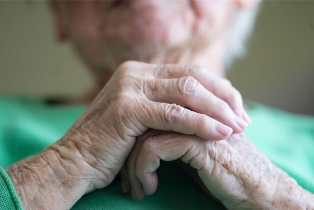 Eine Seniorin faltet ihre Hände.