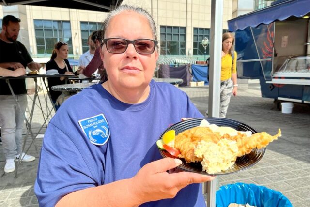 Fisch-Sommelière Andrea Niesel zeigt auf dem Wochenmarkt in Dortmund einen Teller mit Backfisch.