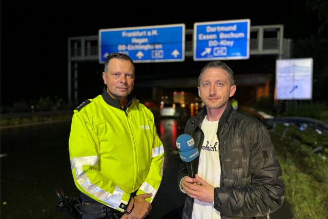Reporter Phillipp Pohl mit dem Einsatzleiter der Polizei – im Hintergrund erkennt man die Unfallstelle