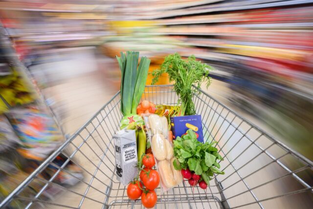 Ein mit Lebensmittel gefüllter Einkaufswagen wird durch einen Supermarkt geschoben. (Symbolbild)