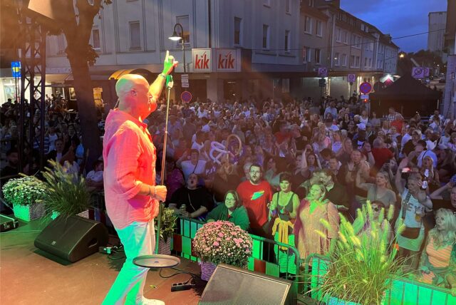 Olaf Henning beim Westerholter Sommerfest 2024 auf der Bühne, vor ihm die Crowd in der Bahnhofstraße.
