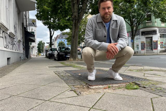 Jan Heisig-Schwarz hockt vor einem Schlagloch auf einem Bürgersteig in der Saarlandstraße in Dortmund.