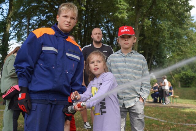 Kind spritzt mit Löschrohr der Feuerwehr.