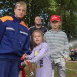 Kind spritzt mit Löschrohr der Feuerwehr.