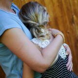 Ein Mädchen wird von seiner Mutter in den Arm genommen und getröstet.