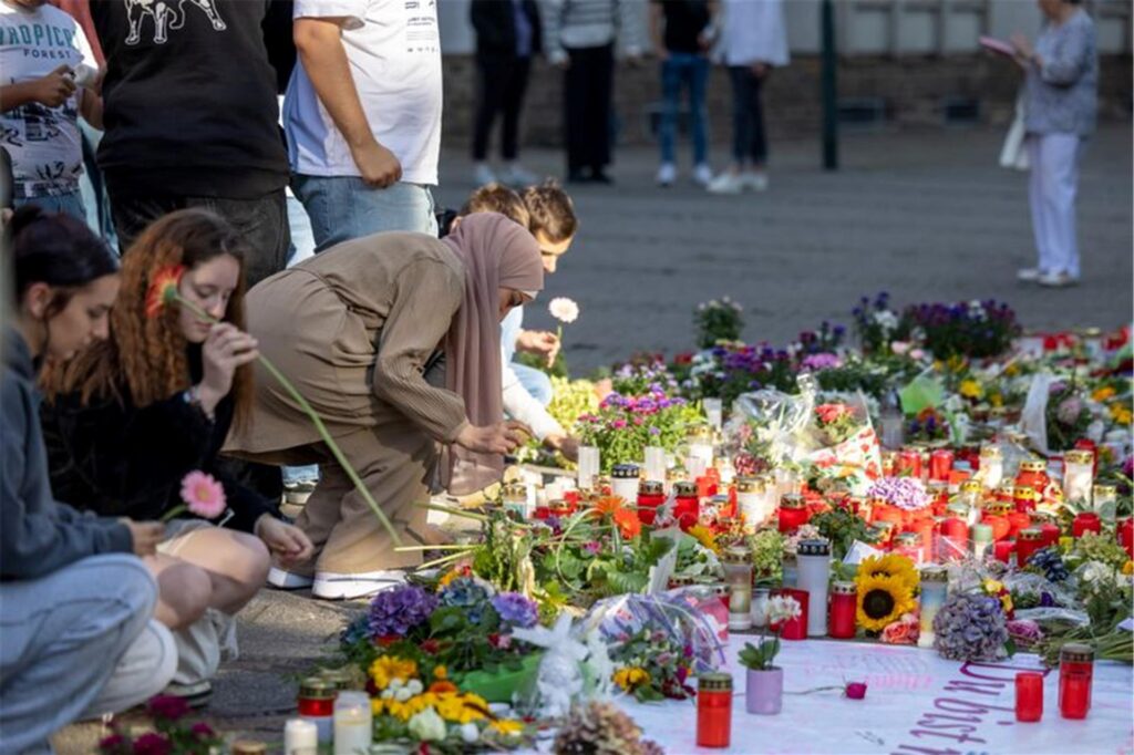 Menschen legen in der Nähe des Tatorts in Solingen Blumen und Kerzen zum Gedenken der Opfer nieder. Menschen legen in der Nähe des Tatorts in Solingen Blumen und Kerzen zum Gedenken der Opfer nieder.
