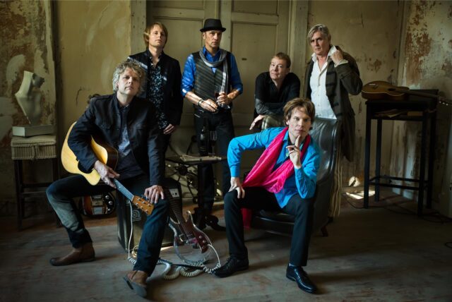 Die Rolling-Stones-Cover-Band „Voodoo Lounge“ posiert mit ihren Instrumenten in einem alten Gebäude vor einer alten Tür.