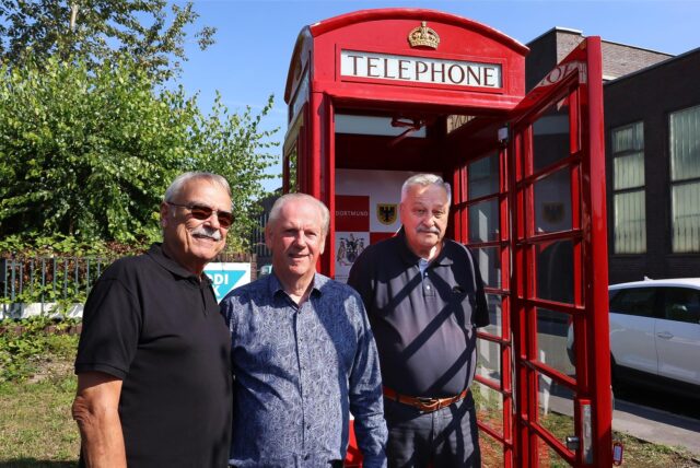 Drei Männer stehen vor einer alten, roten Telefonzelle aus Leeds.
