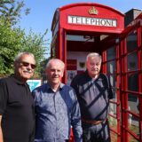Drei Männer stehen vor einer alten, roten Telefonzelle aus Leeds.