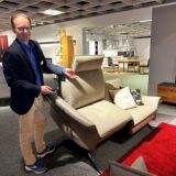 Mann zeigt ein Sofa in einem Laden.