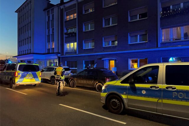 Polizeiwagen stehen vor einem Haus.