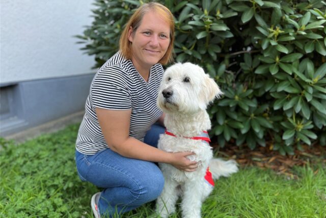 Jessica Ochs kniet neben ihrem Goldendoodle Kimba.