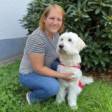 Jessica Ochs kniet neben ihrem Goldendoodle Kimba.