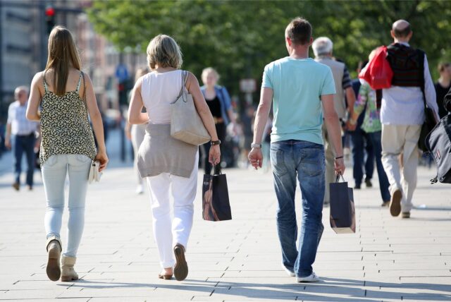 Passanten mit Einkaufstüten laufen durch die Innenstadt.
