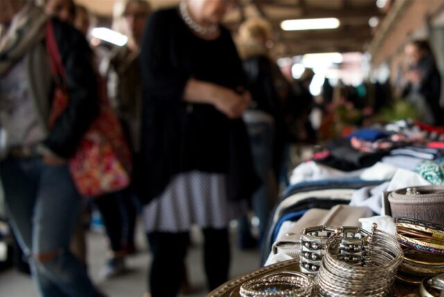 Trödelmarktbesucher schlendern an Ständen voller Schmuck und Kleidung vorbei.