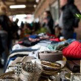 Trödelmarktbesucher schlendern an Ständen voller Schmuck und Kleidung vorbei.