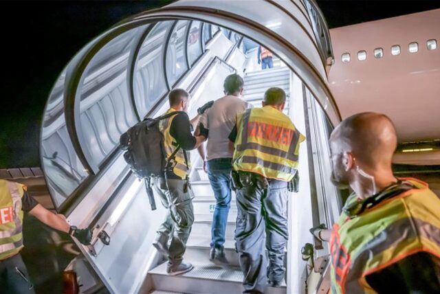 Geflüchtete, die abgeschoben werden sollen, werden in ein Flugzeug geführt.