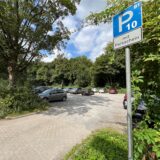 Autos stehen auf einem Kies-Parkplatz.
