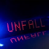 Das Blaulicht auf einem Fahrzeug der Polizei leuchtet in der Dunkelheit, während auf dem Display der Hinweis «Unfall» zu lesen ist.