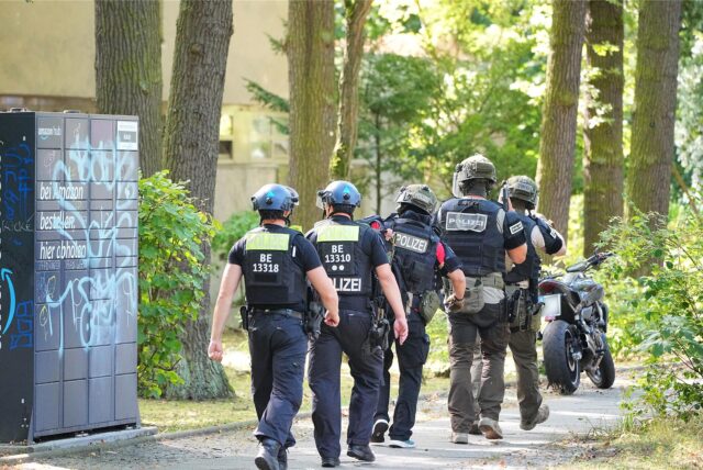 Polizisten eines Spezialeinsatzkommandos (SEK) gehen zu einem Mehrfamilienhaus in Berlin.