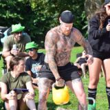 Ein Mann mit tätowiertem Oberkörper beim Gewichtstoßen
