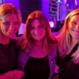 Drei Frauen lächeln in die Kamera.