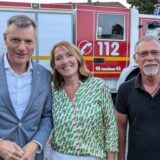 Bürgermeister Tesche, eine Frau und ein Mann lächeln in die Kamera. Hinter ihnen steht ein Feuerwehrwagen.