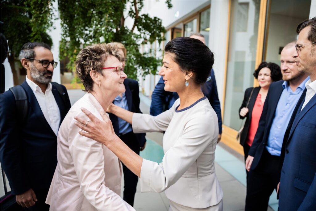 Sabine Zimmermann und Sahra Wagenknecht umarmen sich umringt von anderen Parteimitgliedern.