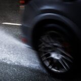 Wasser auf einer Straße spritzt hinter einem Fahrzeug hoch.