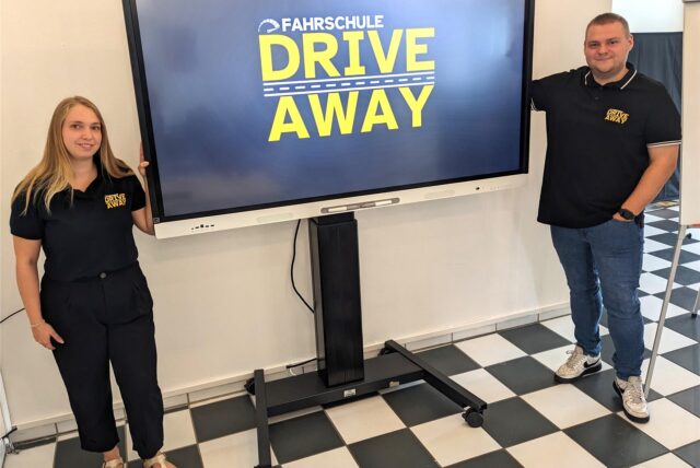 Annkatrin und Dennis Haak stehen in ihrer neuen Fahrschule „Drive Away“ in Dorsten neben einem Smartboard.