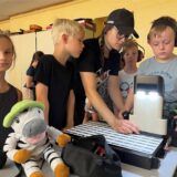Kinder stehen an einer CNC-Fräse.