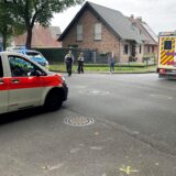 Ein Rettungswagen und ein Notarzt-Einsatzfahrzeug stehen auf einer Straße. Polizisten schauen sich die Unfallspuren an.