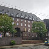 Das Polizeipräsidium Recklinghausen von außen. Auf dem Parkplatz vor dem Gebäude stehen Polizeiautos.