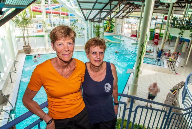 Petra Anlauf und Birgit Berszuk lehnen sich im Copa Ca Backum an einen Handlauf und blicken in die Kamera. Im Hintergrund erstreckt sich das Hallenbad.