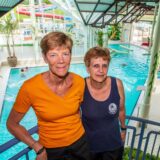 Petra Anlauf und Birgit Berszuk lehnen sich im Copa Ca Backum an einen Handlauf und blicken in die Kamera. Im Hintergrund erstreckt sich das Hallenbad.