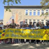Schüler der Cottenburgschule stehen mit einem breiten Banner. Auf dem steht: Alle Kinder haben die gleichen Rechte.