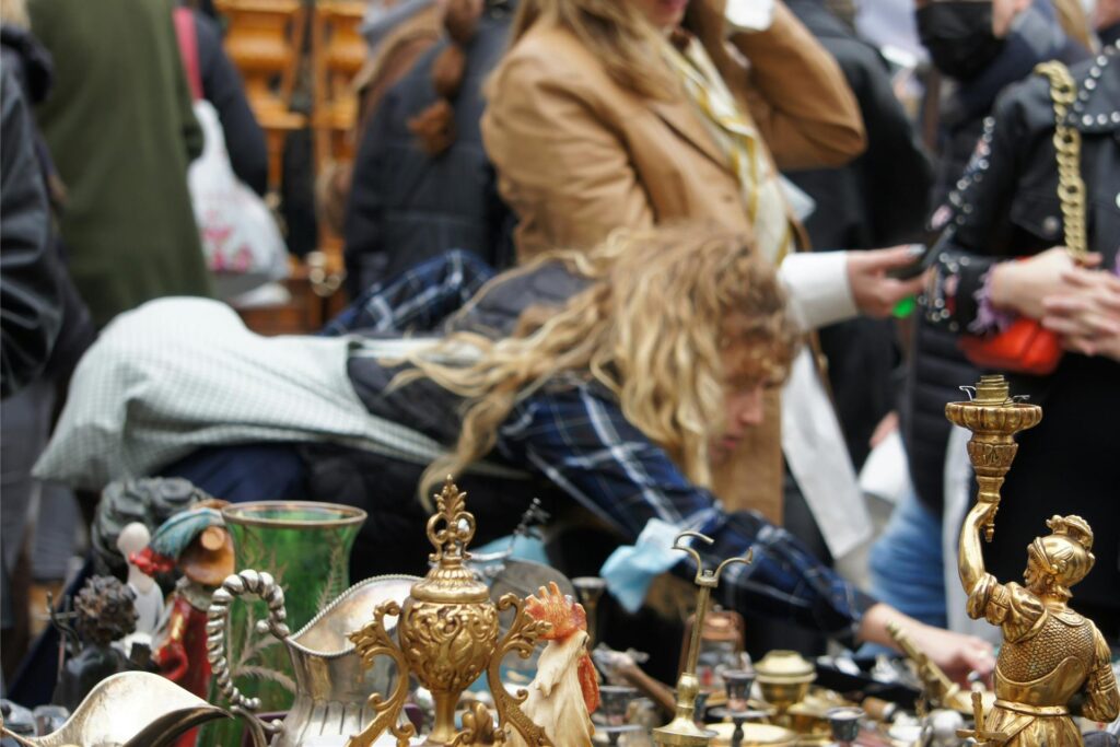 Eine Frau durchstöbert einen Stand auf einem Flohmarkt. Eine Frau durchstöbert einen Stand auf einem Flohmarkt.