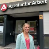 Sandra Haarmann steht vor dem Eingang der Arbeitsagentur in Herten und lächelt in die Kamera.