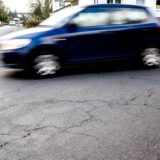 Ein blaues Auto fährt zügig auf einer Straße.