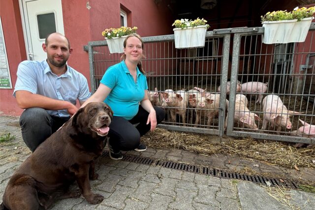 Daniel Kappel und Uta Dingebauer vor einem Gatter mit Ferkeln.