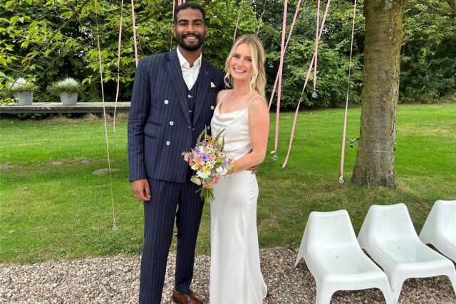 Chantal und Guru Ravindran stehen an der Traulocation vor einem Baum.