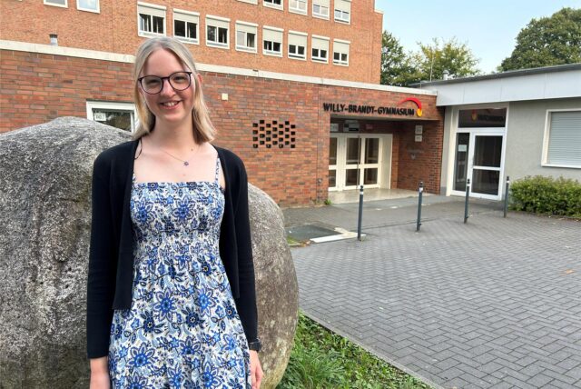 Marieke Petek steht vor dem Eingang des Willy-Brandt-Gymnasiums in Oer-Erkenschwick.