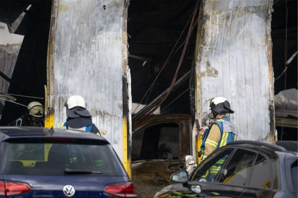 Feuerwehrmänner stehen nach einem Großbrand vor einer Autowerkstatt. Feuerwehrmänner stehen nach einem Großbrand vor einer Autowerkstatt.