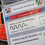 Auf einem Display vor der Leitstelle der Feuerwehr Düsseldorf sind die verschiedenen Sirenensignale zur Warnung der Bevölkerung abgebildet.