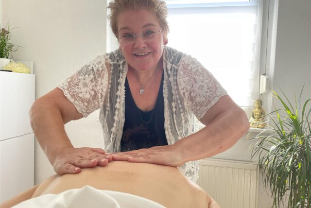 Tanja Moulton hält die Hände auf dem Rücken der Person auf einer Massageliege.